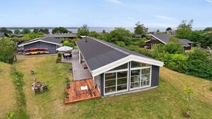 A modern house with a large deck, a covered patio, and a view of the water. - 5 Star Holiday Home in Olsted (Olsted)