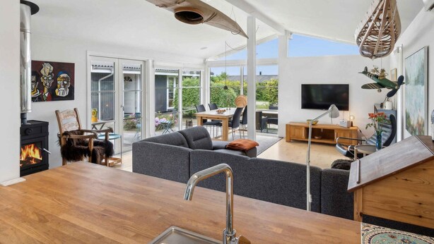A modern living room with a large window, a fireplace, and a dining area. - 5 Star Holiday Home in Olsted (Olsted)