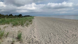 A sandy beach with grassy dunes and a cloudy sky. - 5 Star Holiday Home in Karrebaeksminde (Karrebæksminde)
