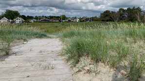 A pathway leading to houses with a grassy field and cloudy sky. - 5 Star Holiday Home in Karrebaeksminde (Karrebæksminde)
