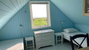 A small, single-room attic bedroom with a sloped ceiling, a window with a view of the outdoors, a bed, a chair, a small table, and a dresser. - 5 Star Holiday Home in Karrebaeksminde (Karrebæksminde)
