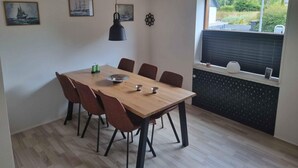 Ein Essbereich mit einem Holztisch, sechs Stühlen, einer Pendelleuchte und Bildern an den Wänden.