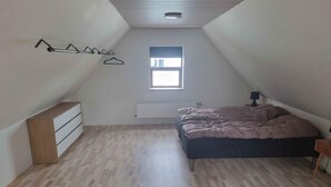 Ein Schlafzimmer mit einem Bett, einem Schminktisch, einem Heizkörper und einem Fenster.