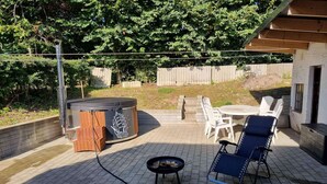 Ein Terrassenbereich mit Whirlpool, Sitzgelegenheit und einer Holzterrasse.