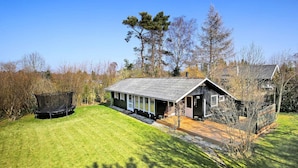 A single-story house with a sloped roof, a front porch, and a trampoline in the yard. - 5 Star Holiday Home in Vejby (Vejby)