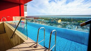 A rooftop pool with glass railings and a view of the cityscape.