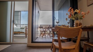 A room with a dining area, a bed, and a view through a glass door to an outdoor seating area.