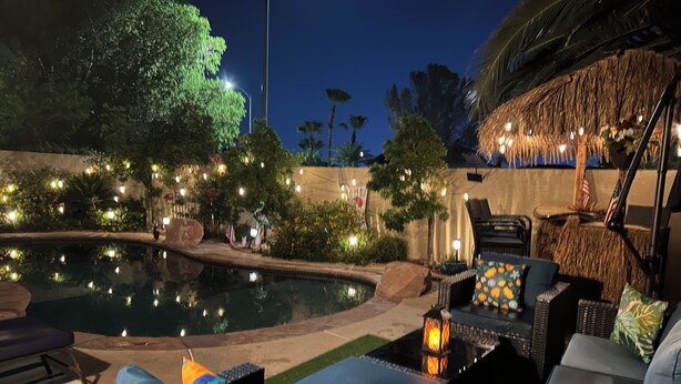 Un área de piscina con sillones de descanso y un bar tiki.