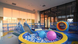 Zona de juegos interior con piscina de pelotas, toboganes y estructuras para escalar.