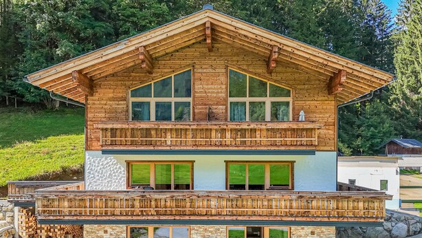 A two-story wooden chalet with a balcony, stone facade, and large windows. - Two Alpine flats with charm (Wald im Pinzgau)