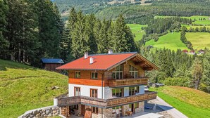 A two-story chalet with a red-tiled roof, a balcony, and a stone foundation. - Two Alpine flats with charm (Wald im Pinzgau)