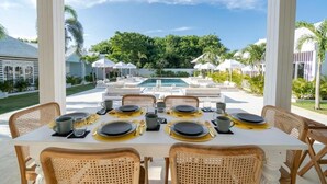 A dining area with a table set for four, overlooking a pool and lush greenery. - RIA ULUWATU Tropical Chic Hotel (Pecatu)