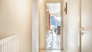 A hallway leading to a balcony with a view of the sky and a building. - Cosy family flat centrally located (Koksijde)