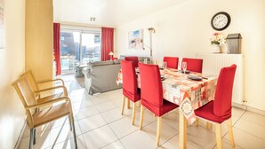 A dining area with a table set for six, red chairs, a clock, and a radiator. - Cosy family flat centrally located (Koksijde)