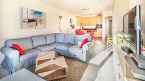 A modern living room with a sectional sofa, a coffee table, and a flat-screen TV. - Cosy family flat centrally located (Koksijde)