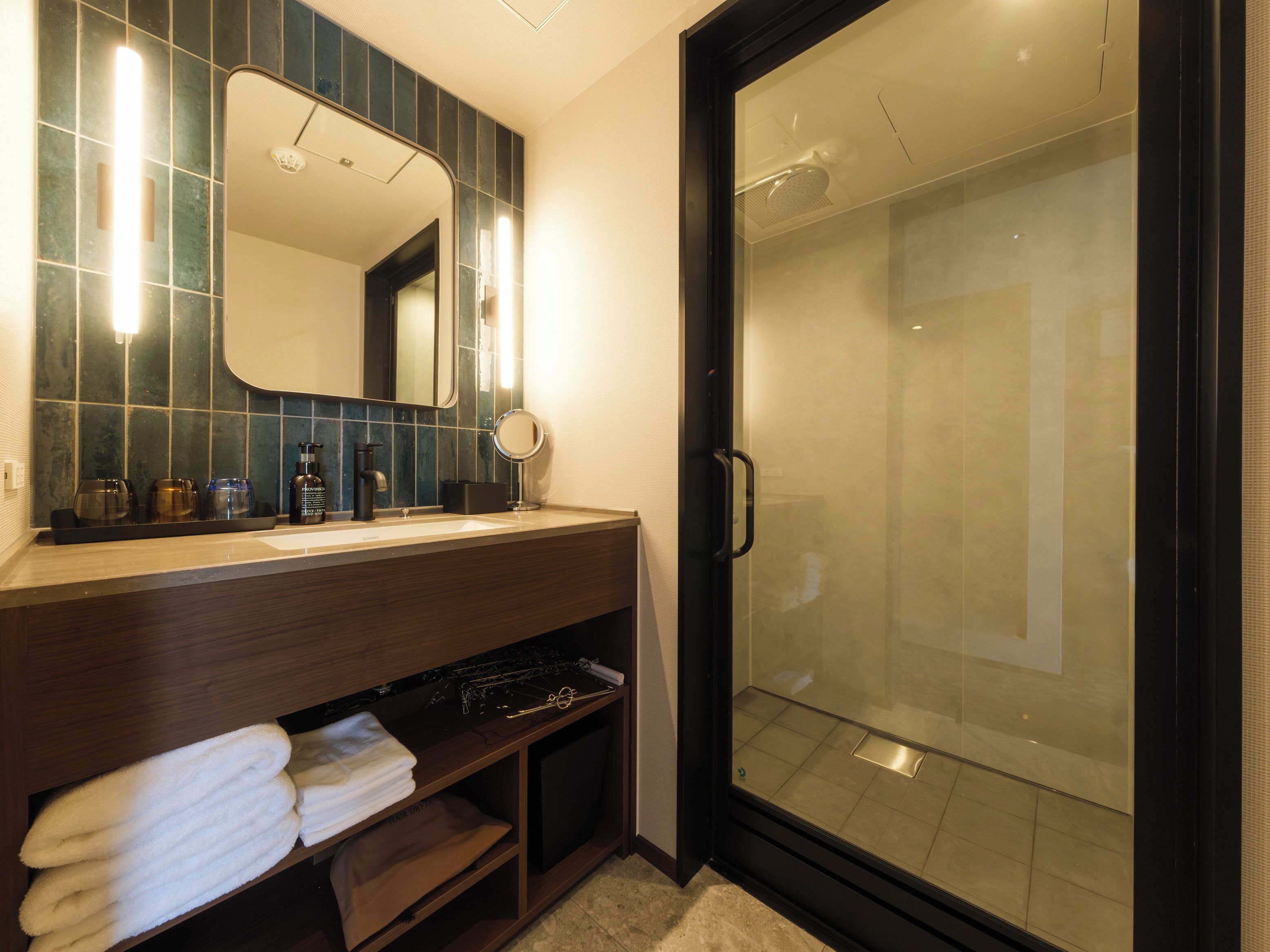 A bathroom with a mirror, sink, and shower.