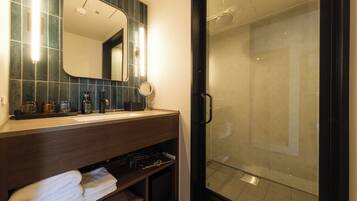 A bathroom with a mirror, sink, and shower.