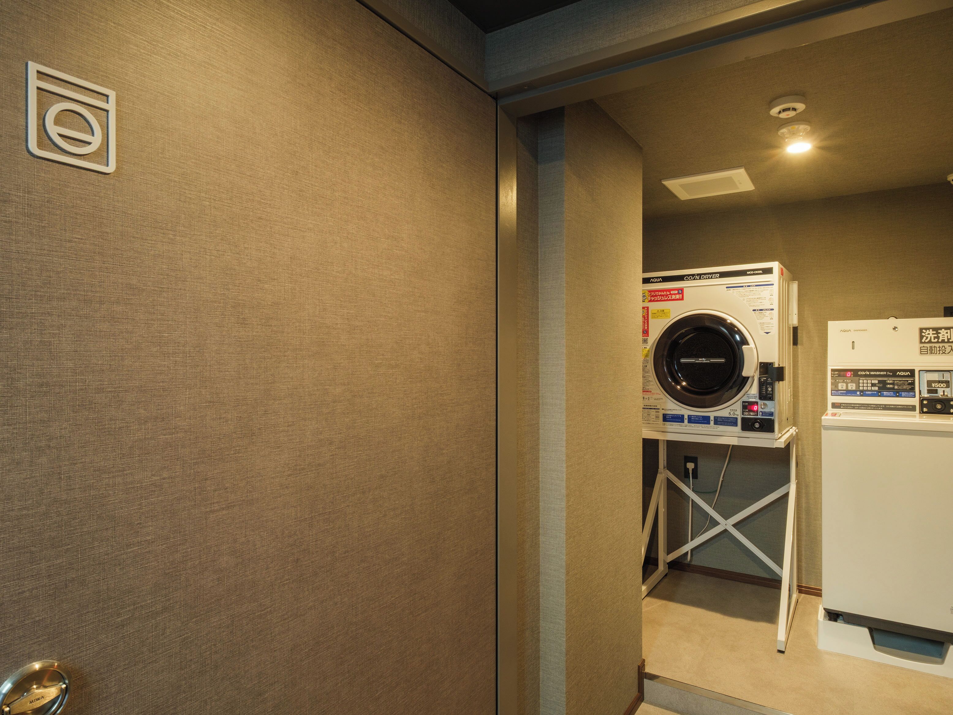 A laundry room with a front-loading washing machine, a dryer, and a control panel.