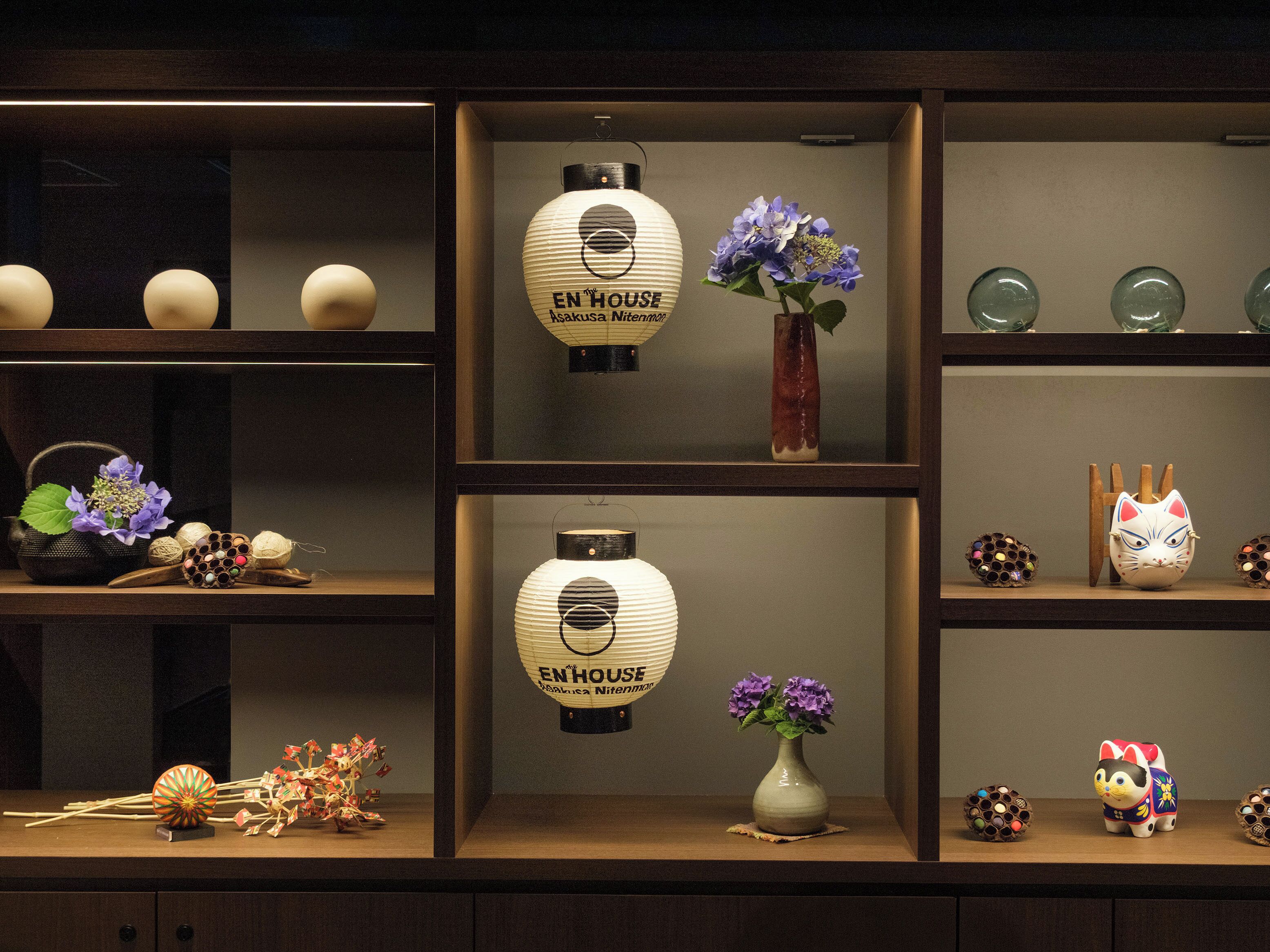 Een presentatie van diverse objecten, waaronder vazen, een katbeeldje en decoratieve items, op planken.