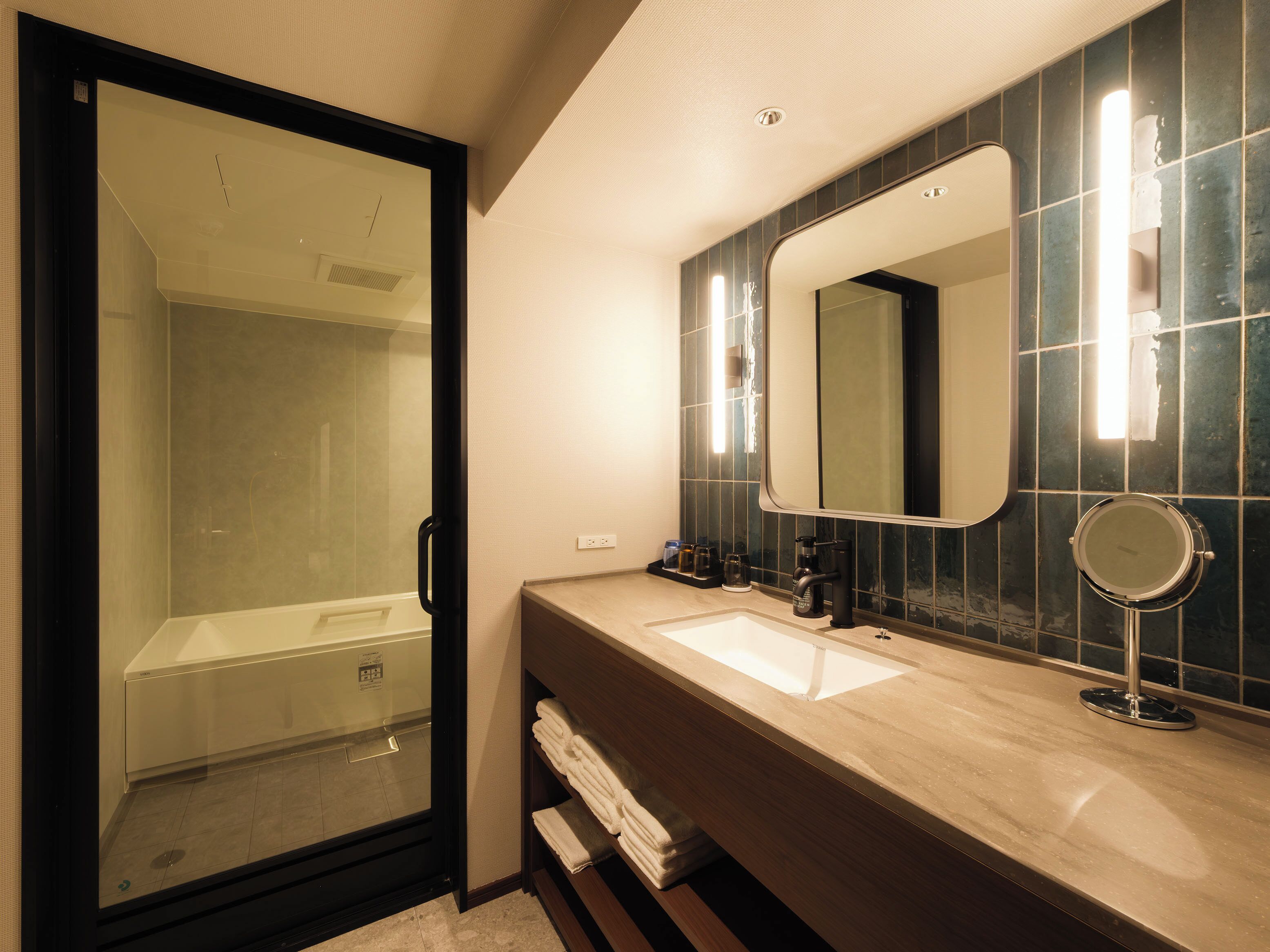 A modern bathroom with a glass shower enclosure, a sink with a mirror, and a towel rack.