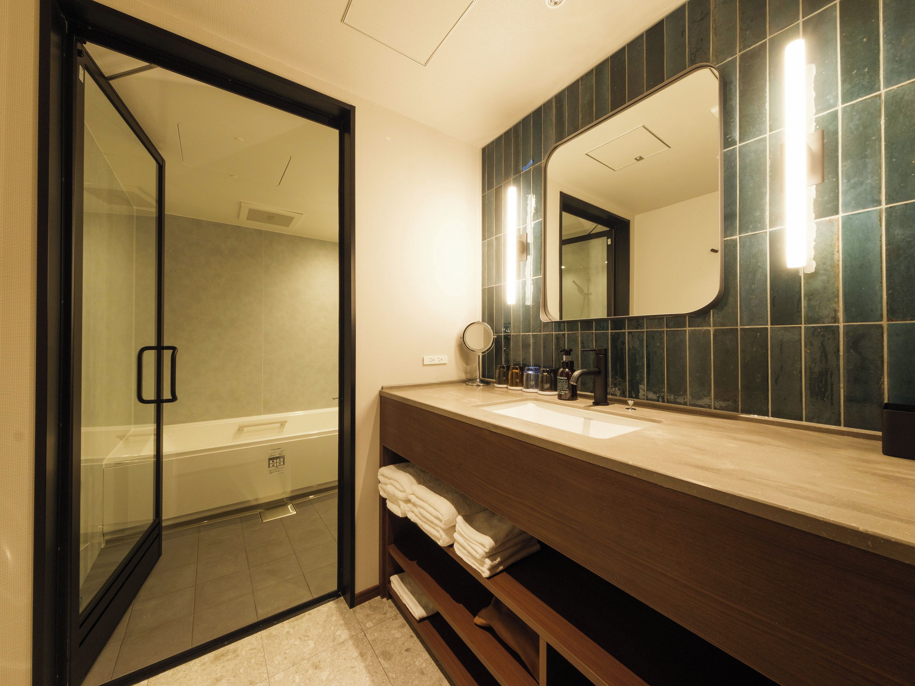A bathroom with a glass shower door, a sink with a mirror, and a towel rack.