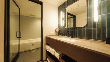 A bathroom with a glass shower door, a sink with a mirror, and a towel rack.