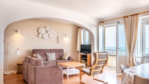A modern living room with a sofa, coffee table, and a TV stand. - Spacious family flat with sea view (Koksijde)