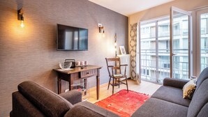Een moderne woonkamer met een flatscreen televisie, een houten bijzettafeltje en een rode vloerkleed.
