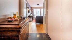 Een gang met een houten dressoir, een eettafel met stoelen en een bank op de achtergrond.
