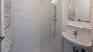 A modern bathroom with a glass shower enclosure, a white sink, and a mirror above the sink. - Stylish flat with sea view (Koksijde)