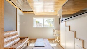 Una sala de estar moderna con un sofá de cuero, una mesa de centro de madera y una silla blanca.
