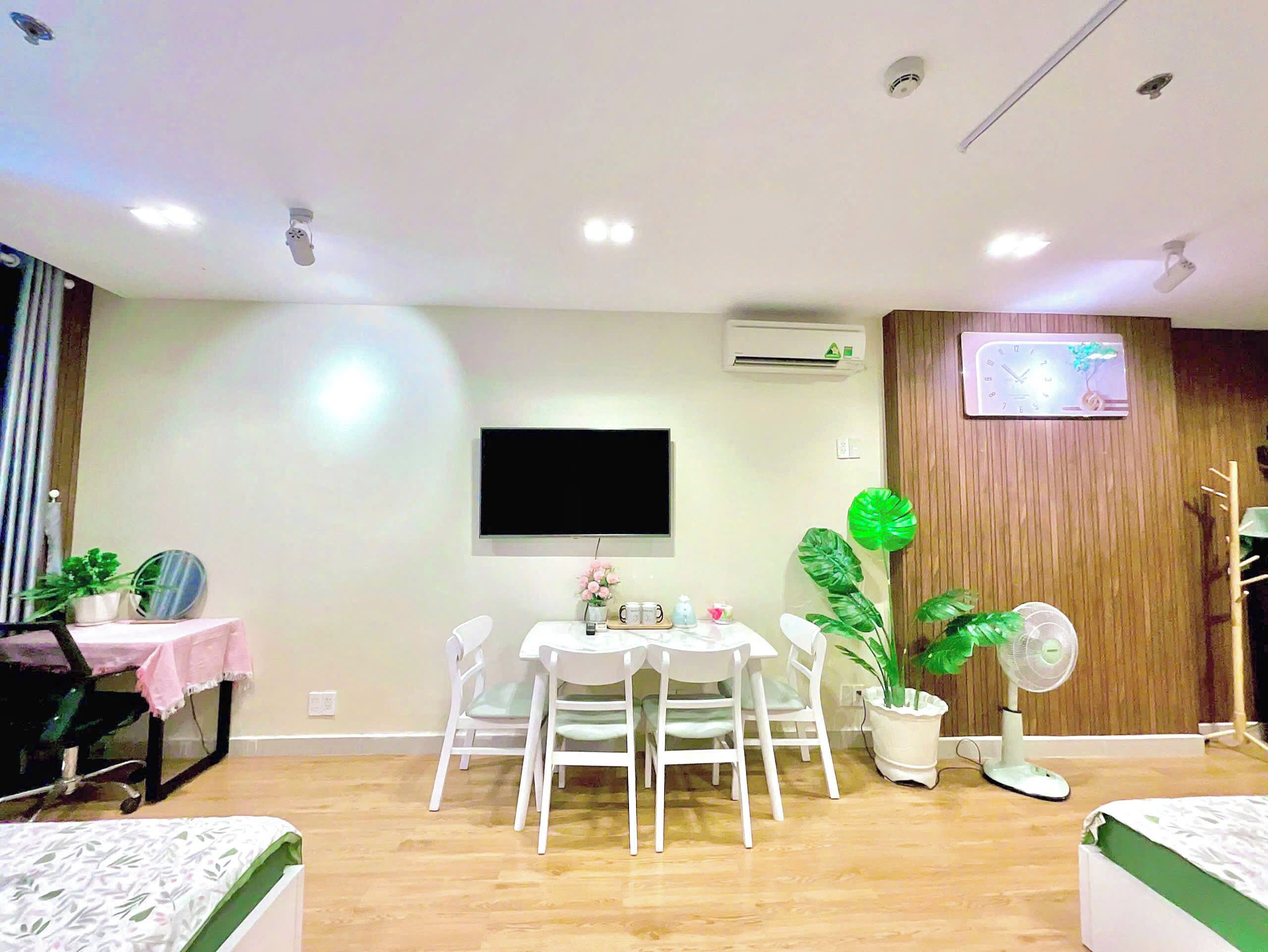 Una sala de estar moderna con comedor, un televisor de pantalla plana en la pared y un panel de madera en un lateral.
