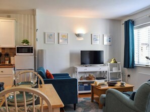 Un salon moderne avec un téléviseur, un canapé et un coin repas.