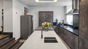 Una cucina moderna con isola centrale, mobili scuri e cappa aspirante in acciaio inossidabile.