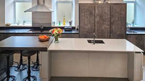 Una cucina moderna con isola centrale, sgabelli da bar, un'ampia finestra e forno a incasso.