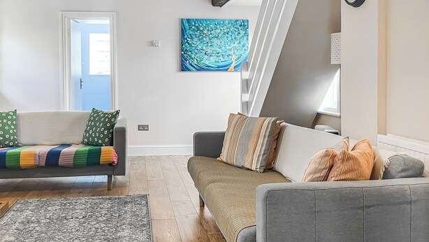 Ein modernes Wohnzimmer mit zwei Sofas, einem gemusterten Teppich und einem blauen, abstrakten Gemälde an der Wand.