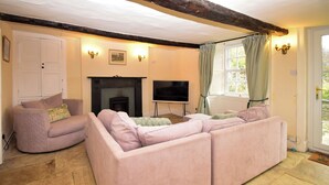 Een woonkamer met een open haard, een televisie en een grote, roze modulaire bank.