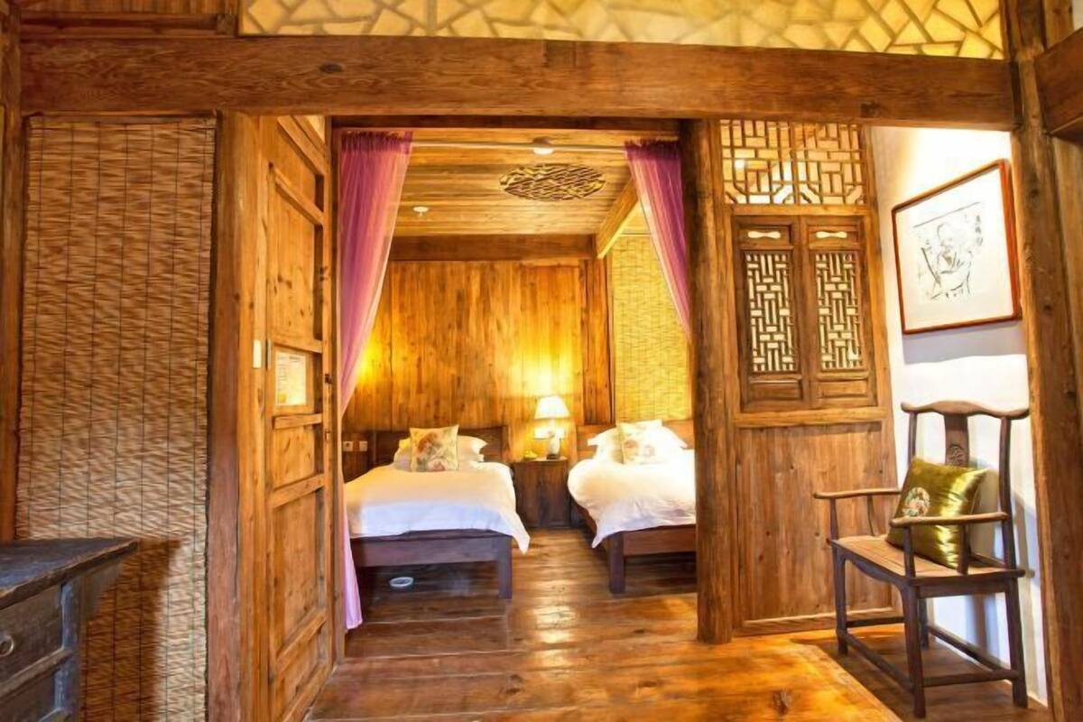A wooden room with two beds, a chair, and a wall with a geometric pattern.