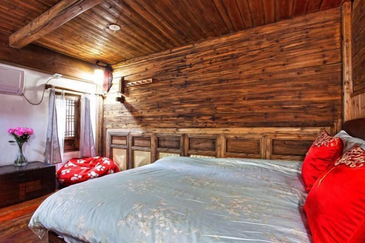 A wooden cabin bedroom with a bed, a nightstand, and a window with curtains.
