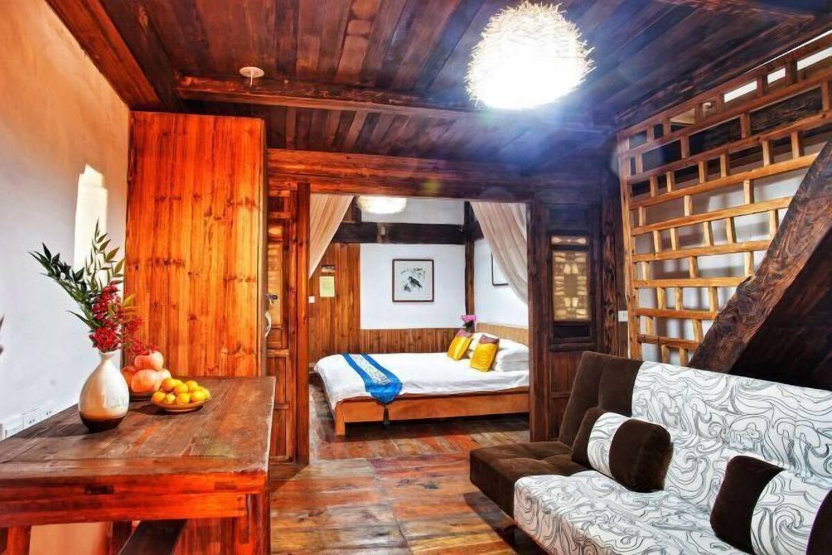 A wooden room with a bed, a sofa, and a table with fruit.