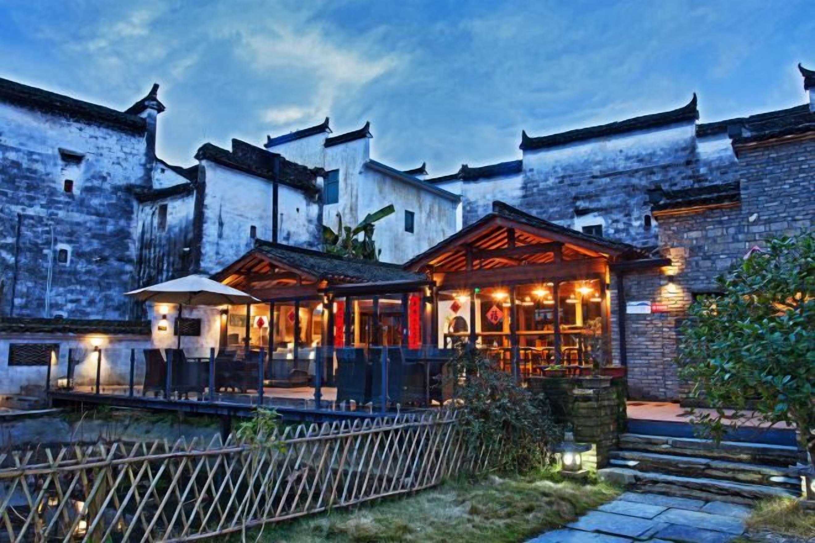 A traditional building with a restaurant area featuring outdoor seating and a wooden fence.