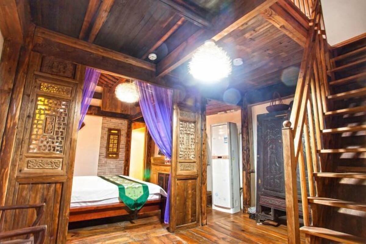 A traditional wooden room with a bed, a wardrobe, and a staircase.