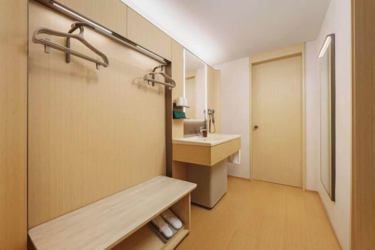 A modern bathroom with a wooden vanity, a mirror, and a bench.