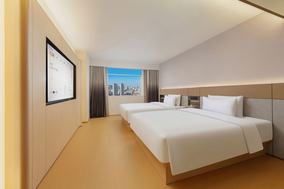 A hotel room with a large bed, a desk, and a city view.