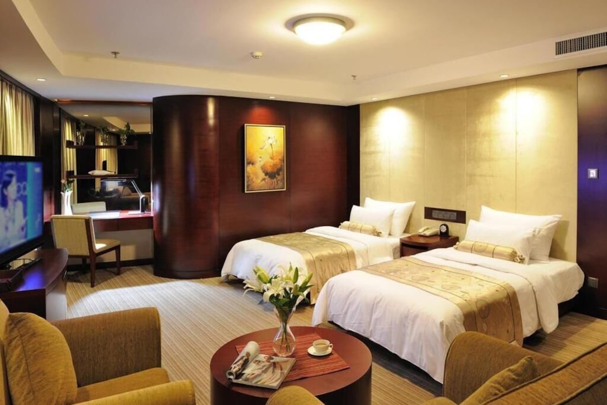 A hotel room with two beds, a TV, a desk, and a chair.