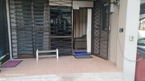 A room with a patterned bed, a small white table, and a blue mat. - Cozy Studio Apartment Wifi Pool (Suva)