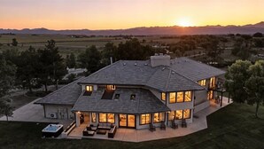 Una casa moderna con un patio amplio, un jacuzzi y vistas a la montaña al atardecer.