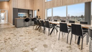 A modern kitchen with a large island, a dining area with a long table and chairs, and large windows offering a view. - "Gillis" - 1km from the sea by Interhome (Glesborg)