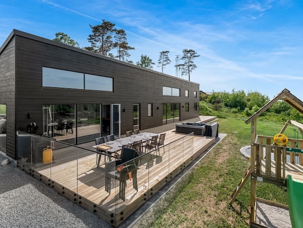 A modern building with a deck, outdoor seating, and a play area.