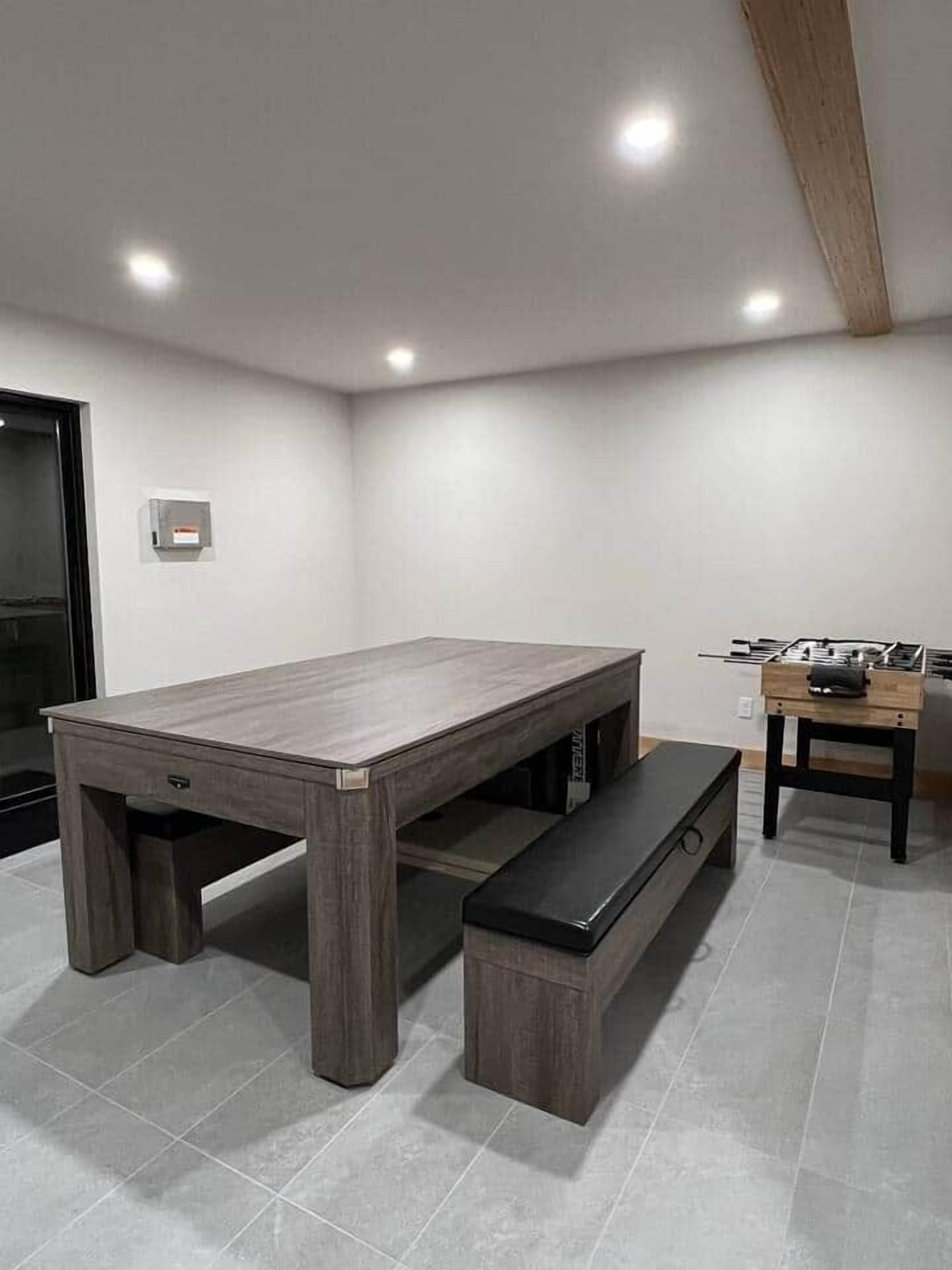 Une pièce moderne avec une table à manger en bois, un banc et un petit coin cuisine équipé d’une cuisinière.